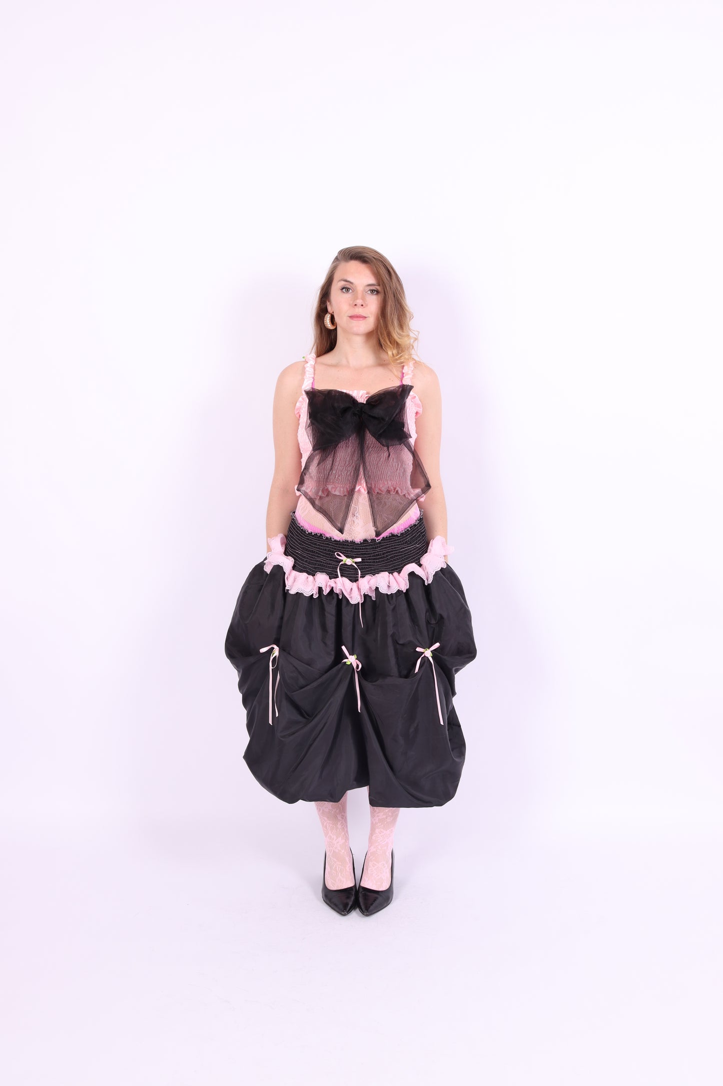 A pink bandeau top with a large black bow on the front, featuring elasticated shirring bodice and ruched shoulder straps. Delta Of Phoenix Giselle Bow Top