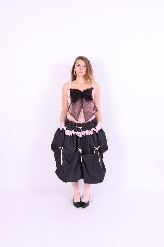 A pink bandeau top with a large black bow on the front, featuring elasticated shirring bodice and ruched shoulder straps. Delta Of Phoenix Giselle Bow Top