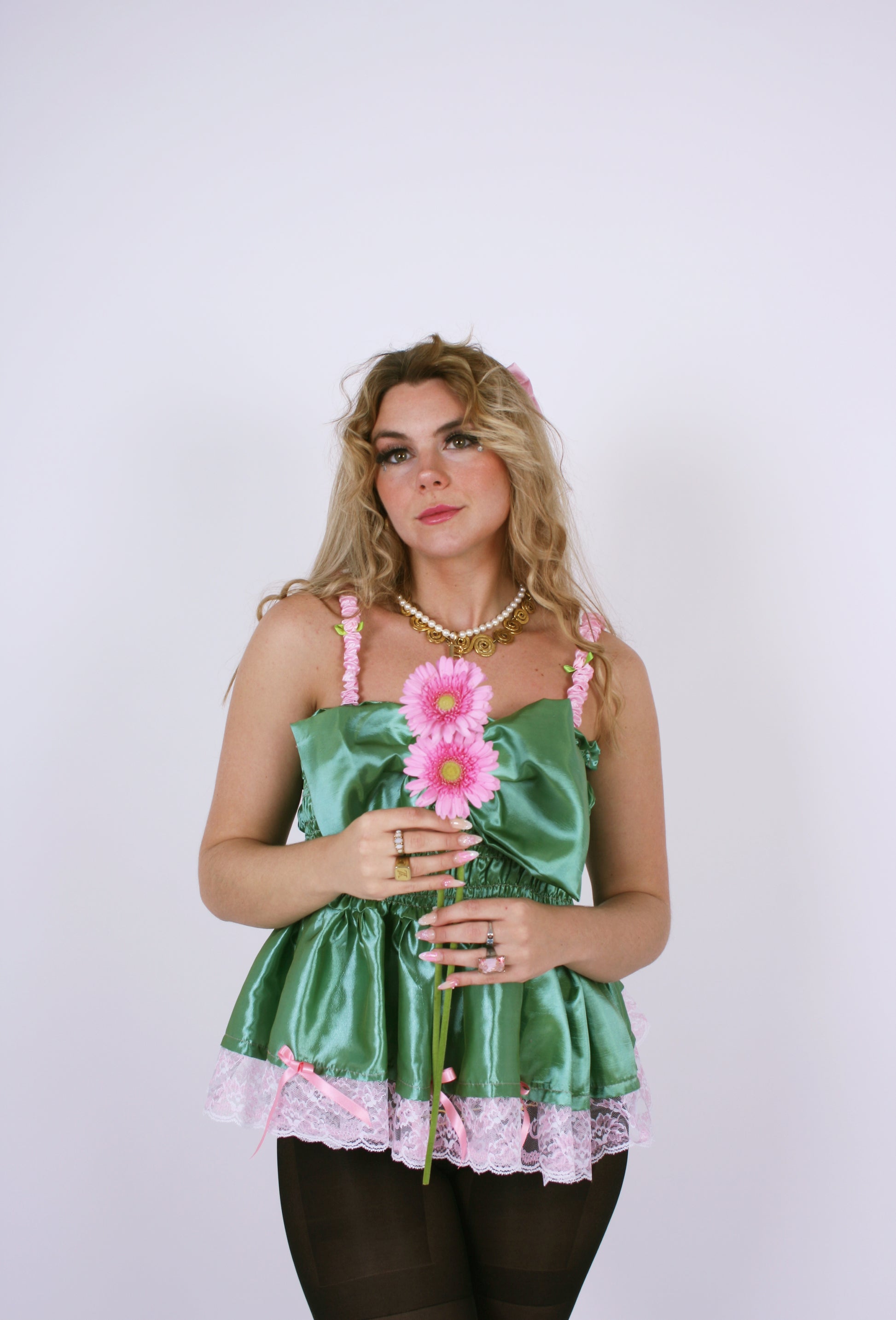 A pistachio green taffeta top with pink scalloped lace detail and a bow on the front, featuring pink topstitch elasticated shirring bodice and baby pink taffeta shoulder straps with rosette detail. Delta Of Phoenix Göta Bow Top