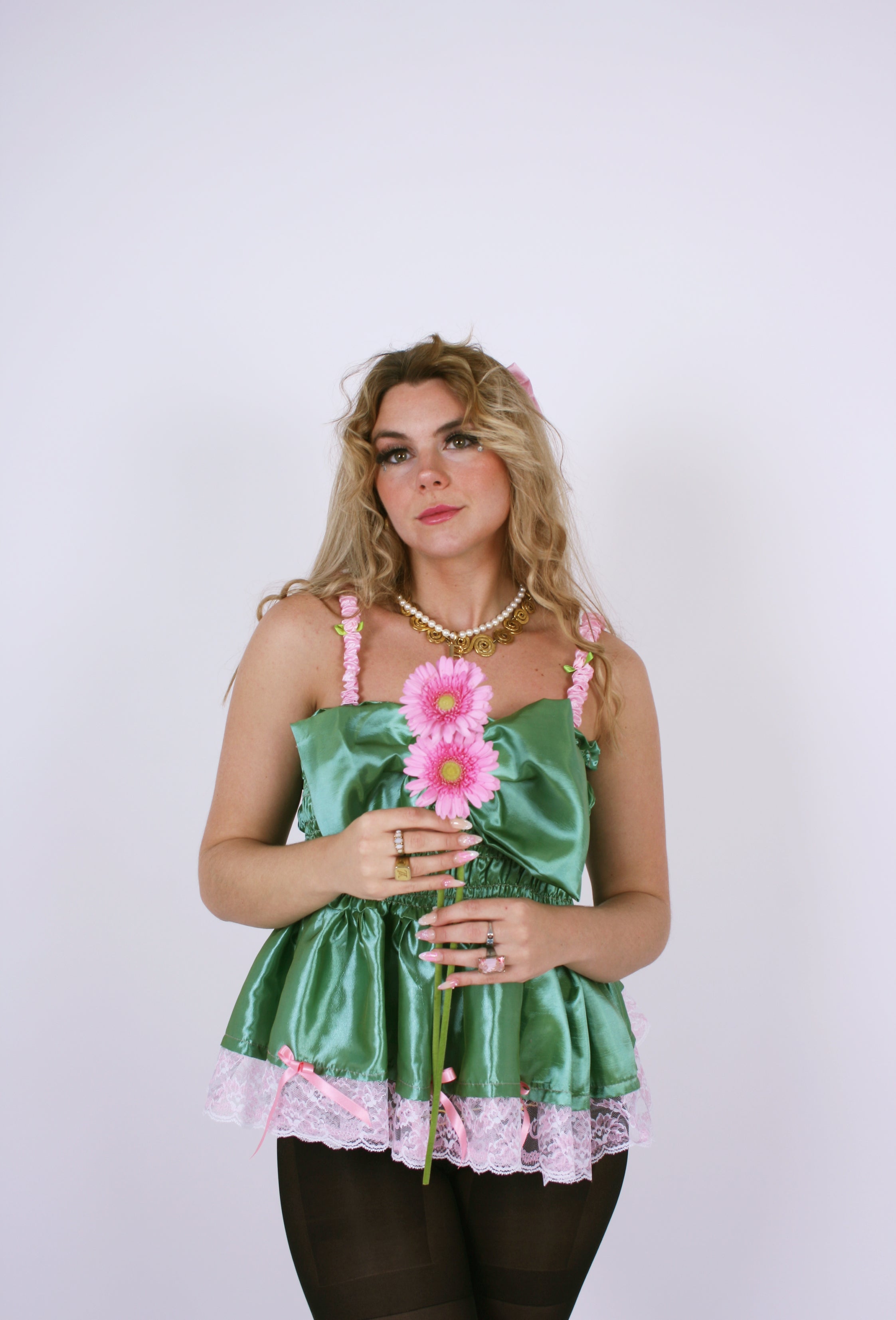 A pistachio green taffeta top with pink scalloped lace detail and a bow on the front, featuring pink topstitch elasticated shirring bodice and baby pink taffeta shoulder straps with rosette detail. Delta Of Phoenix Göta Bow Top