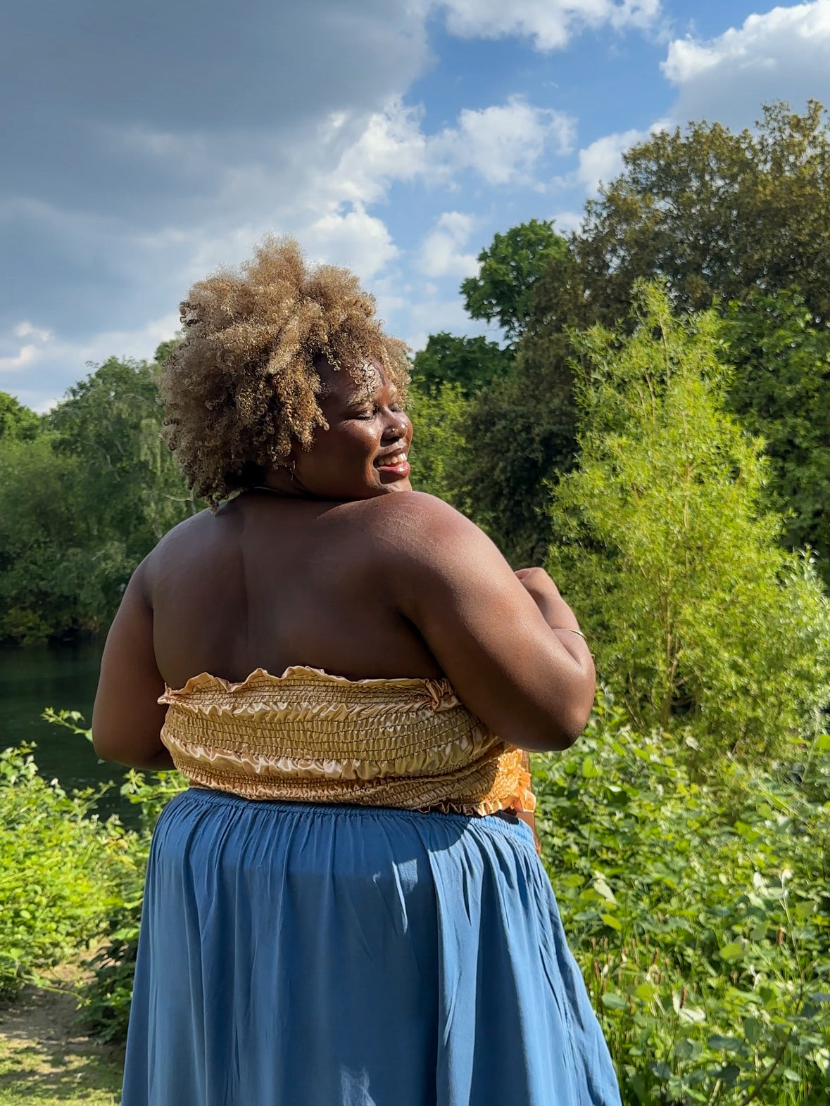 A gold satin top with an elasticated shirring bodice and a terracotta brown organza bow on the front. It features shoulder straps with elasticated and ruched details. Delta Of Phoenix Naomi Bow Top - worn by Naomi Native
