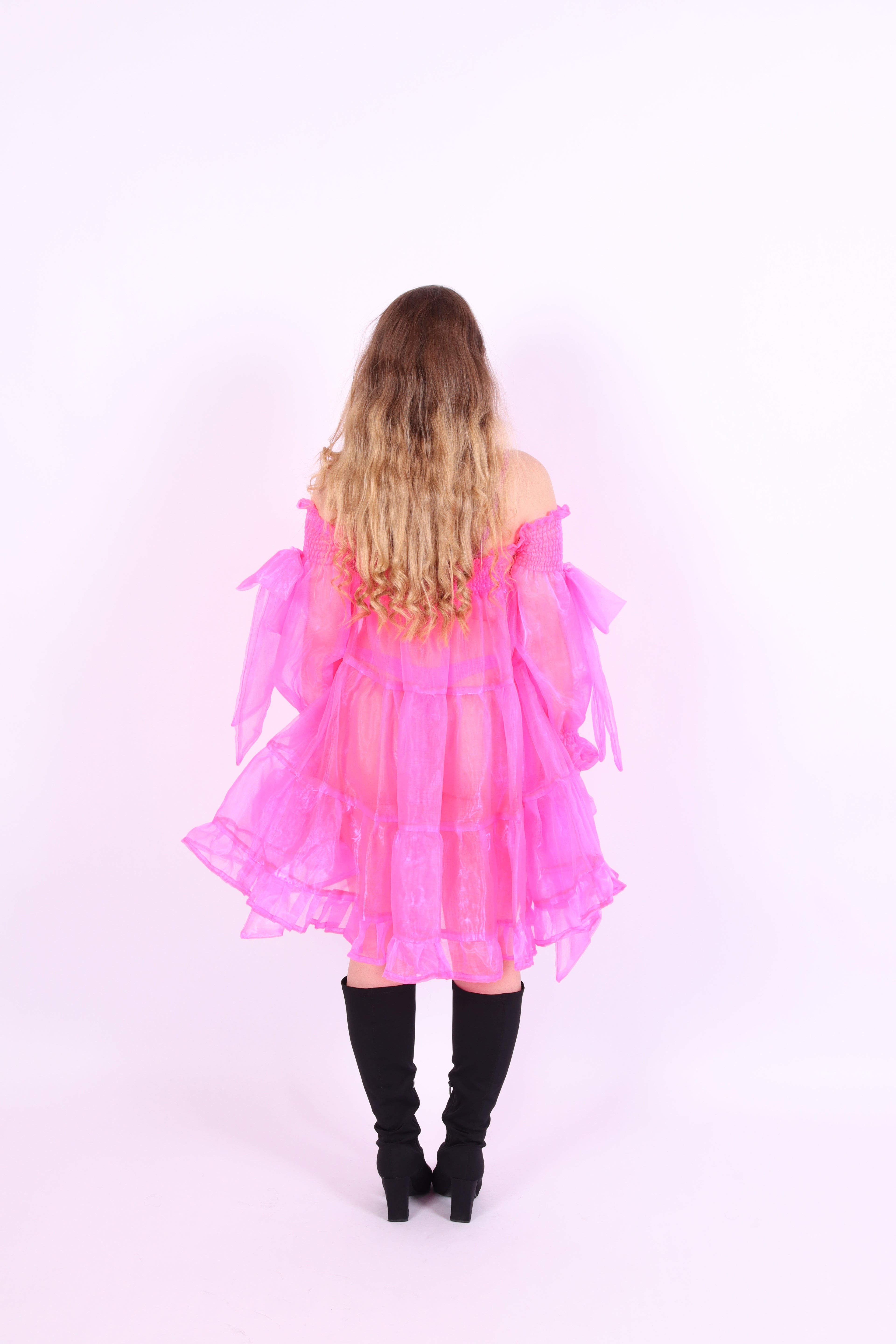 A neon pink organza mini dress with a large bow detail at the sleeve, skirt, and front, featuring a bardot neckline and puff sleeves. Delta Of Phoenix neon pink Cordelia dress