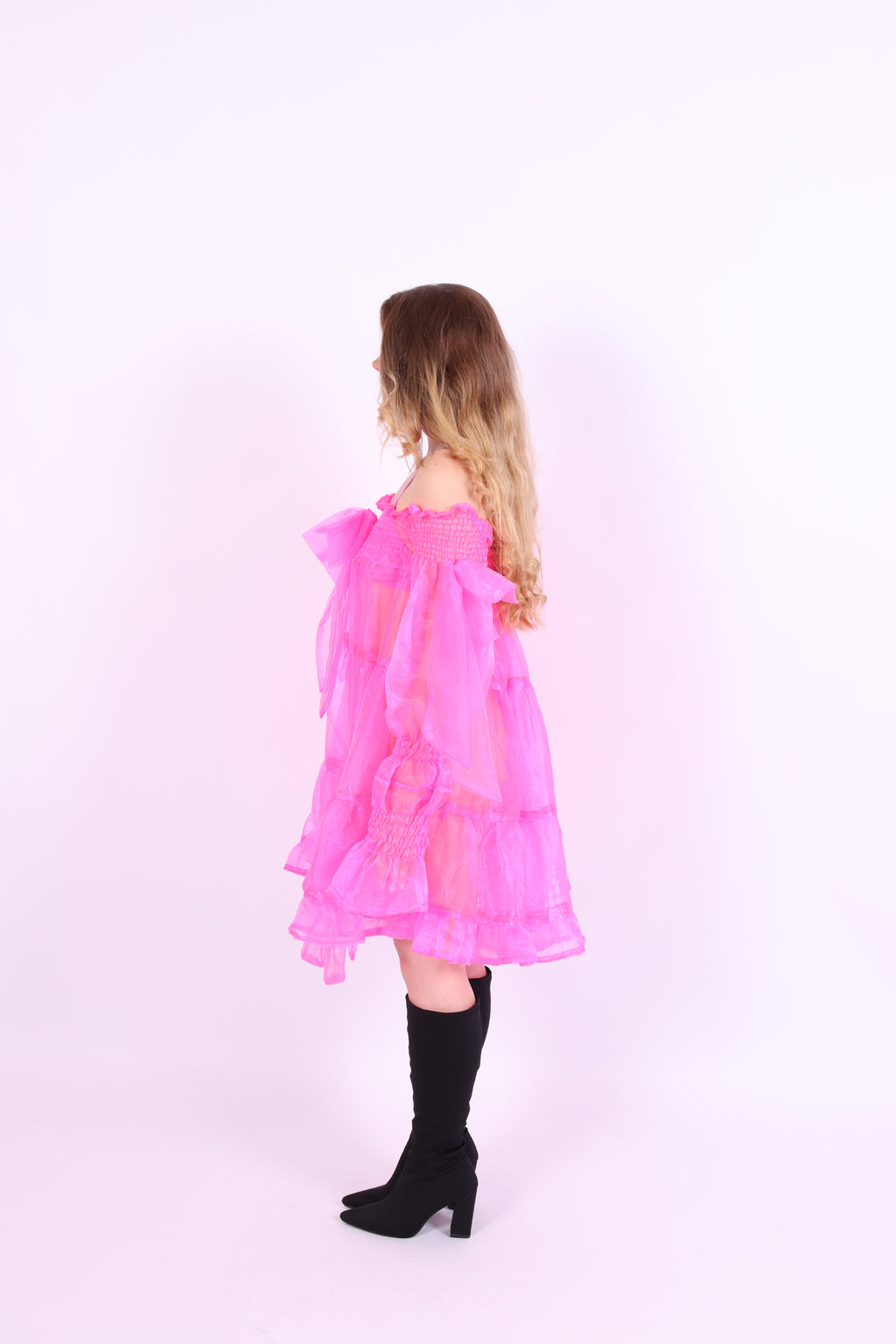A neon pink organza mini dress with a large bow detail at the sleeve, skirt, and front, featuring a bardot neckline and puff sleeves. Delta Of Phoenix neon pink Cordelia dress