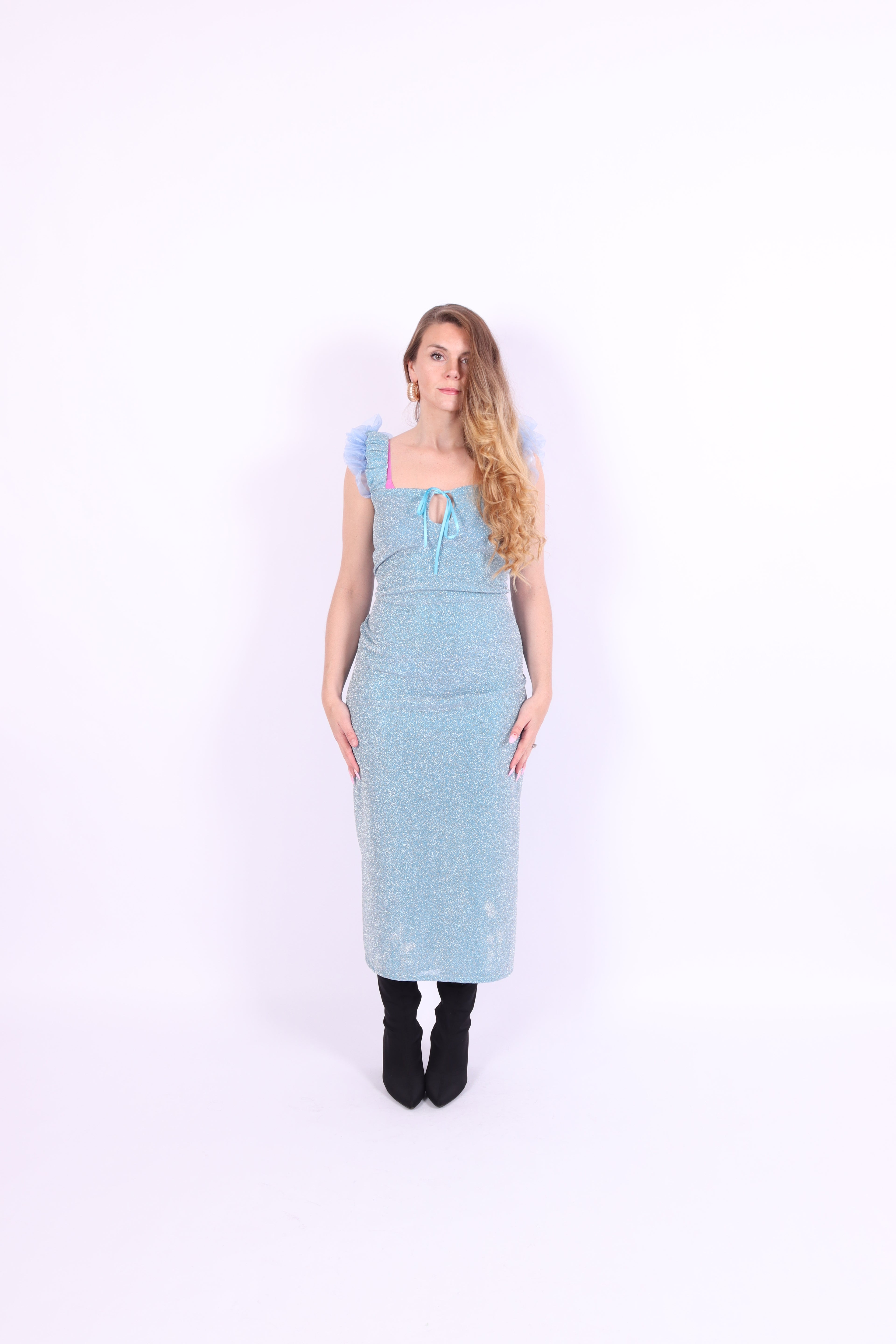 A blue glitter cocktail dress with ruffle detailing, elasticated ruched straps, and a ribbon bow keyhole detail at the front. Delta Of Phoenix Juni Midi Dress