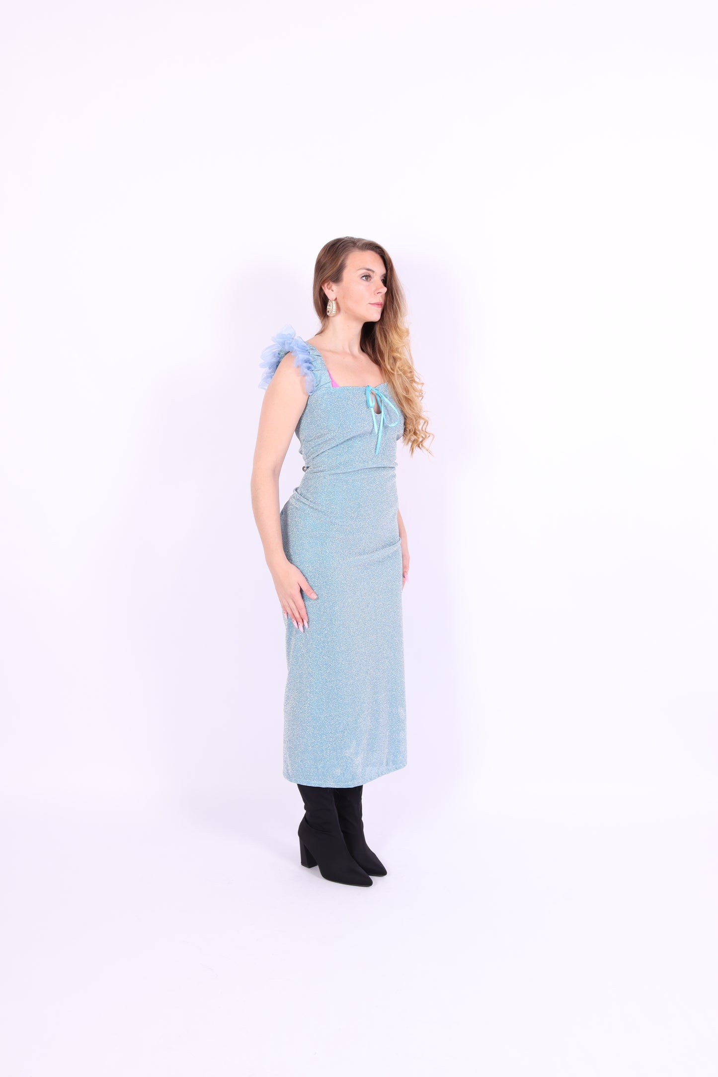 A blue glitter cocktail dress with ruffle detailing, elasticated ruched straps, and a ribbon bow keyhole detail at the front. Delta Of Phoenix Juni Midi Dress