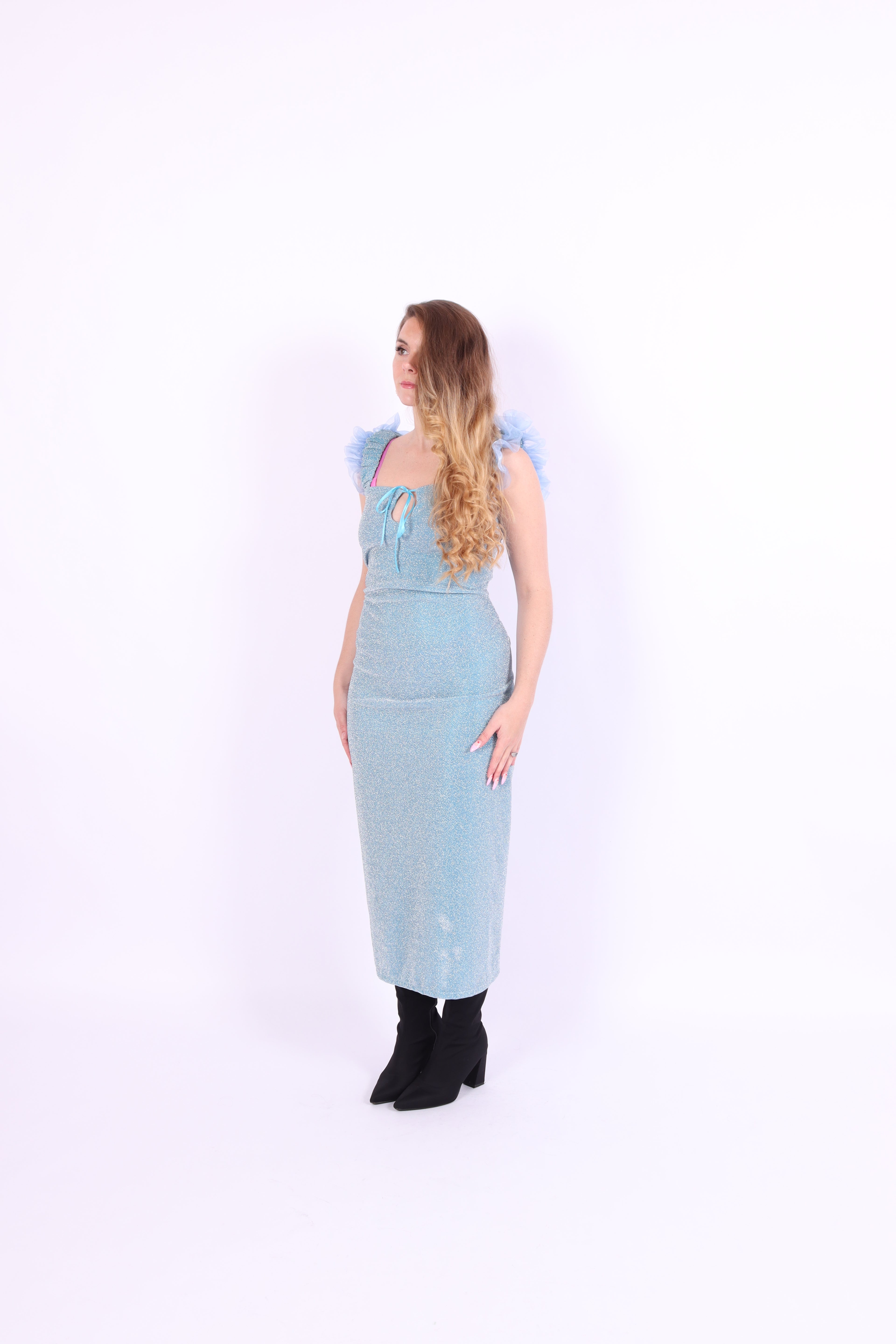 A blue glitter cocktail dress with ruffle detailing, elasticated ruched straps, and a ribbon bow keyhole detail at the front. Delta Of Phoenix Juni Midi Dress