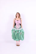 A black satin top with an elasticated shirring bodice and a large bubblegum pink organza bow on the front. It features elasticated shoulder straps with ruched detailing and is displayed against a plain background. Delta Of Phoenix Georgette Bow Top
