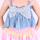 A denim crop top with a large white lace bow and diamante detail on the chest, pink topstitch elasticated shirring across the top bodice, and full babydoll gathered panel. It features elasticated shoulder straps with pink ribbon bow detail. Delta Of Phoenix Gigi Bow Top