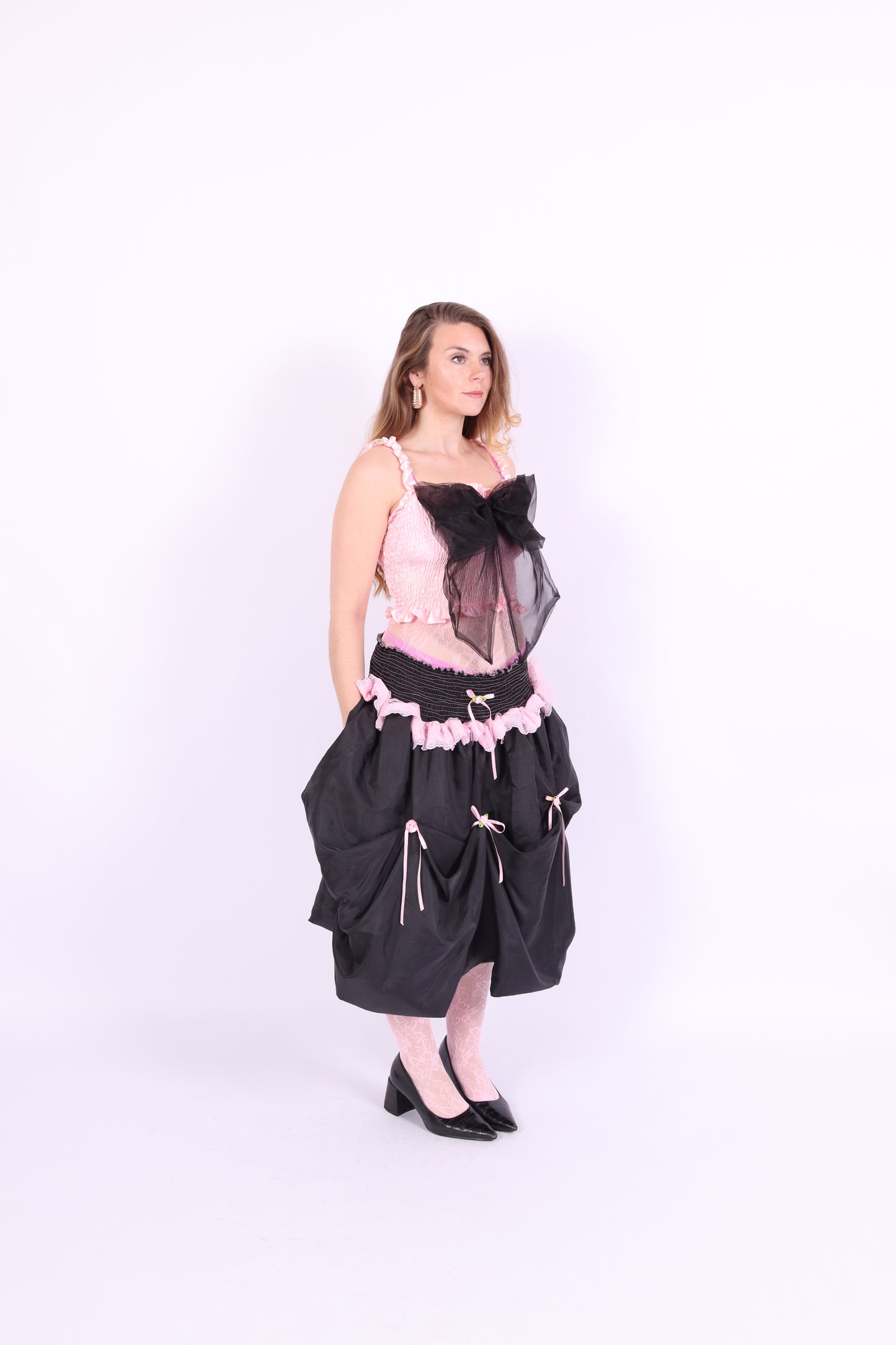 A pink bandeau top with a large black bow on the front, featuring elasticated shirring bodice and ruched shoulder straps. Delta Of Phoenix Giselle Bow Top