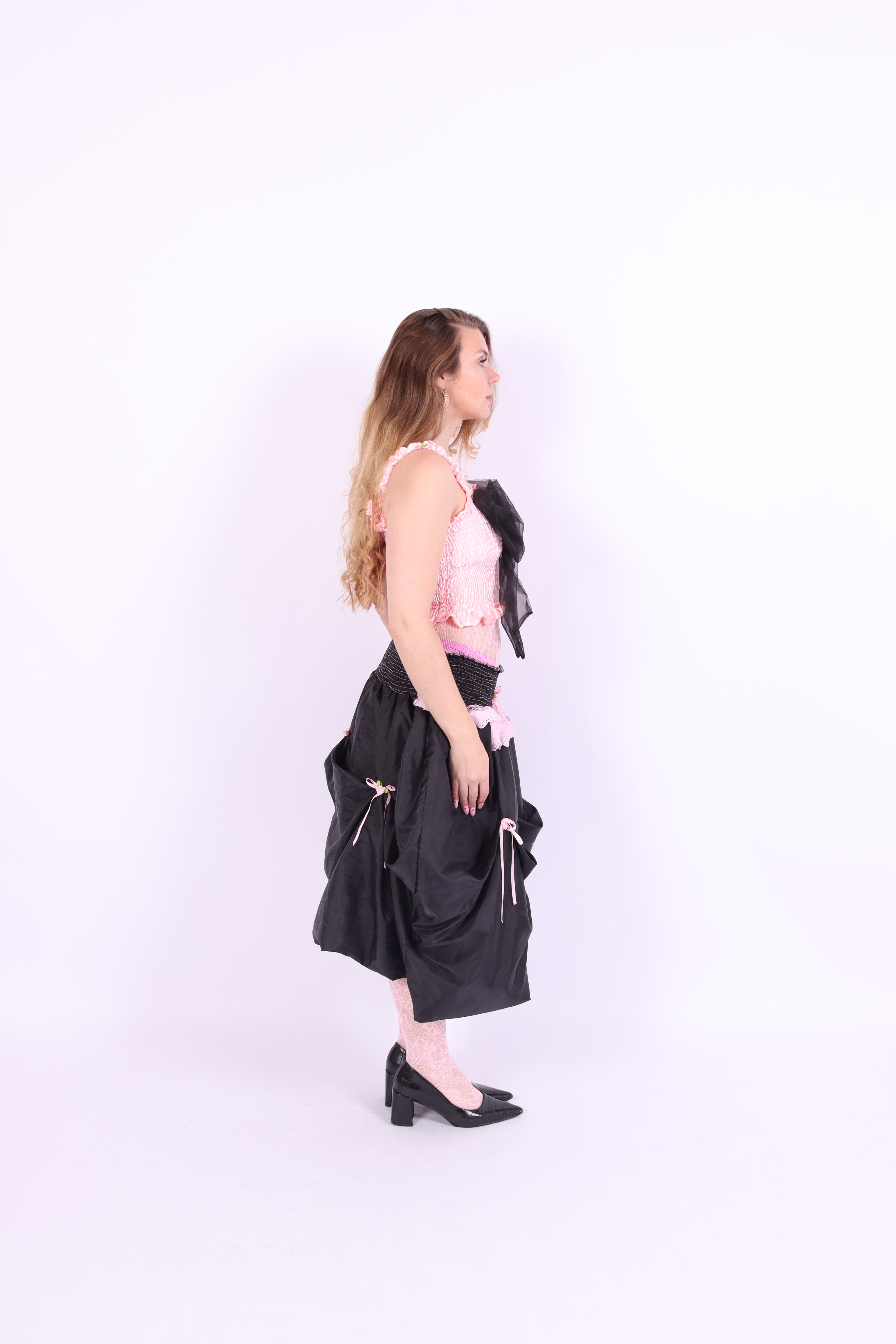 A pink bandeau top with a large black bow on the front, featuring elasticated shirring bodice and ruched shoulder straps. Delta Of Phoenix Giselle Bow Top